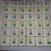 Rows of cake squares decorated with pink and green frosting