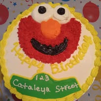 Character cake decorated with a smiling red, yellow, orange, black, and white face