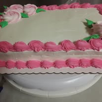 Rectangular sheet cake decorated with pink frosting borders and flowers